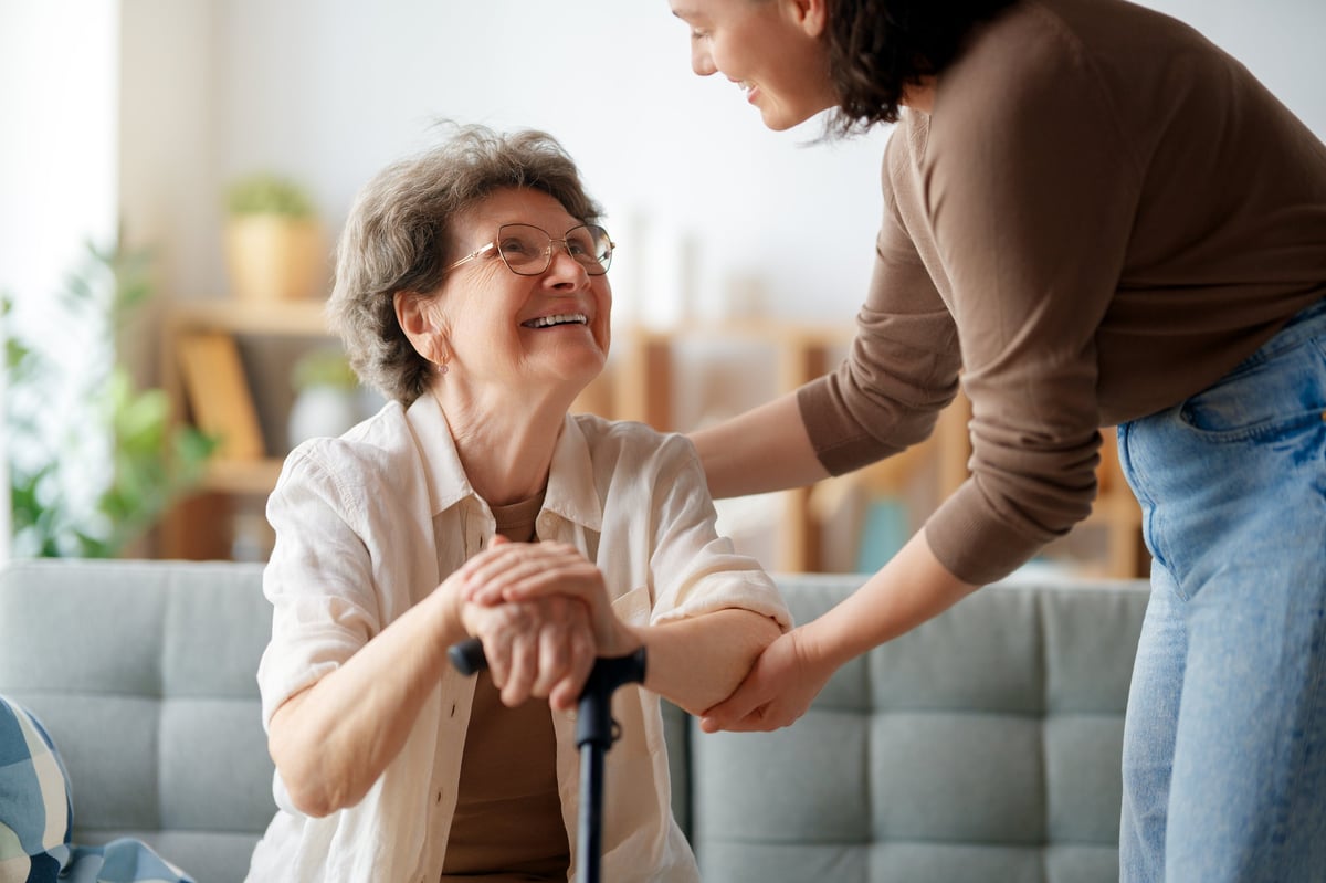 Female caregiver of color sitting with senior woman at home